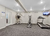 Thumbnail 5 of 8 - A spacious home gym with a treadmill, elliptical trainer, and stationary bike.