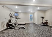 Thumbnail 4 of 8 - A spacious home gym with a television and exercise equipment.