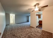 Thumbnail 29 of 33 - an empty living room with a ceiling fan and a kitchen
