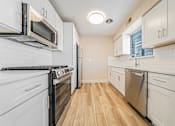 Thumbnail 13 of 25 - A kitchen with white appliances and wooden floors.