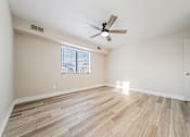 Thumbnail 15 of 25 - A room with a ceiling fan and wooden flooring.