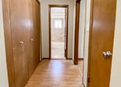 Thumbnail 11 of 18 - a long hallway with wooden doors and a door to a bathroom