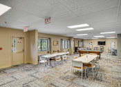 Thumbnail 11 of 30 - A room with tables and chairs and an exit sign on the ceiling at Independence Place Apartments, Parma Heights, 44130