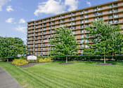 Thumbnail 2 of 30 - A large apartment building with a lawn in front and a sign that says at Independence Place Apartments, Parma Heights, 44130
