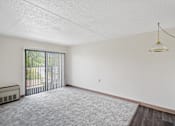 Thumbnail 25 of 30 - A room with a grey carpet and a white wall with a hanging light fixture at Independence Place Apartments, Ohio