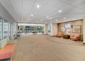 Thumbnail 10 of 30 - A spacious waiting area with orange and beige furniture at Independence Place Apartments, Parma Heights