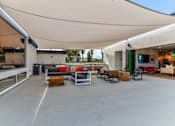 Thumbnail 11 of 17 - A modern outdoor seating area with a white canopy and concrete floor.