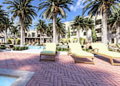 Thumbnail 11 of 12 - a pool area with lounge chairs and palm trees