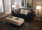 Thumbnail 33 of 75 - a living room with a black couch and a white ottoman at The Crossings at Redlands, Redlands