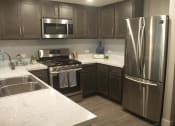 Thumbnail 49 of 75 - a kitchen with dark cabinets and white countertops at The Crossings at Redlands, California, 92374