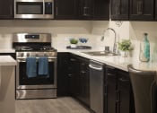 Thumbnail 41 of 75 - a kitchen with black cabinets and stainless steel appliances at The Crossings at Redlands, Redlands