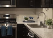 Thumbnail 64 of 75 - a kitchen with black cabinets and white marble countertops at The Crossings at Redlands, Redlands, CA