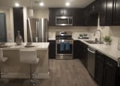 Thumbnail 43 of 75 - a kitchen with dark cabinets and white countertops at The Crossings at Redlands, Redlands