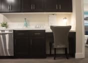 Thumbnail 58 of 75 - a kitchen with black cabinets and a white counter top with a chair in front of it at The Crossings at Redlands, Redlands, CA