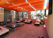 Thumbnail 5 of 12 - Redlands, CA, Pet-Friendly Apartments - Circa 2020 - Community Room with Patio Flooring Made of Patterned Pavers with an Overhead Canopy, Sofas, Chaise Lounges, Fire pit, and Mounted Televisions.
