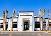 Thumbnail 1 of 12 - A white building with the number 24000 on it and the word "LEASING" on the top.
