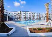 Thumbnail 7 of 12 - A pool surrounded by palm trees and white chairs.