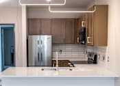 Thumbnail 14 of 16 - A modern kitchen with a white countertop and stainless steel appliances.