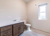 Thumbnail 15 of 16 - A bathroom with a toilet, sink, and a window.