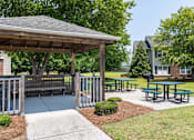 Thumbnail 9 of 10 - A pavilion with picnic tables is surrounded by a fence and a sidewalk at Carriage Hills, Lumberton