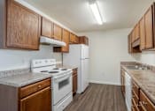 Thumbnail 4 of 10 - A kitchen with white appliances and wooden cabinets at Carriage Hills, Lumberton, NC 28358