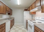 Thumbnail 7 of 10 - A kitchen with white appliances and brown cabinets at Carriage Hills, NC 28358