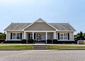 Thumbnail 2 of 10 - A small white house with a black front door and two windows at Carriage Hills, 28358