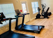 Thumbnail 13 of 23 - A room with a treadmill, a stationary bike and a rowing machine.