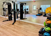Thumbnail 14 of 23 - A gym with a mirror wall and exercise equipment.