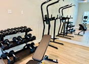 Thumbnail 15 of 23 - A gym with a variety of equipment including dumbbells, weight plates, and a bench.