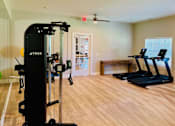 Thumbnail 16 of 23 - A gym with a weight machine and a treadmill.
