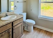 Thumbnail 10 of 23 - A bathroom with a toilet, sink, and a window.