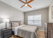 Thumbnail 4 of 23 - A bedroom with a bed, dresser, and ceiling fan.