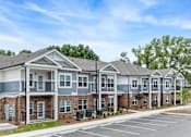 Thumbnail 19 of 23 - A row of townhouses with a parking lot in front.