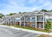 Thumbnail 21 of 23 - A row of townhouses with a parking lot in front.