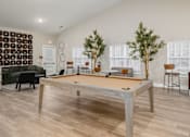 Thumbnail 9 of 23 - A pool table in the middle of a room with a green couch and a tree.