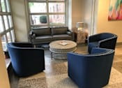Thumbnail 7 of 17 - A living room with a grey couch, two blue chairs and a coffee table at Highland Memorial, NC