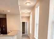 Thumbnail 12 of 17 - A long hallway with a white counter on the side and a brown cabinet.