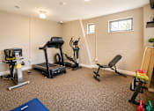 Thumbnail 8 of 17 - A home gym with a treadmill, exercise bike, and weights.