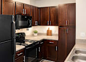 Thumbnail 1 of 17 - A kitchen with black appliances and wooden cabinets.