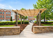 Thumbnail 11 of 17 - A walkway with a wooden pergola and stone walls.