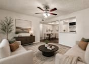 Thumbnail 6 of 17 - A living room with a white couch, a coffee table, and a ceiling fan.