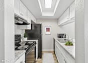 Thumbnail 2 of 31 - A kitchen with a black stove top oven and a black refrigerator.