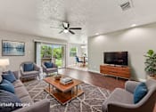 Thumbnail 12 of 64 - A living room with a grey couch, a coffee table, a television, and a ceiling fan.