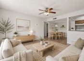 Thumbnail 5 of 17 - A living room with a beige couch, a coffee table, and a ceiling fan.