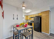 Thumbnail 13 of 24 - A kitchen with a table and chairs in the foreground and a refrigerator in the background.