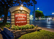 Thumbnail 31 of 34 - A sign for Wellington Estates Apartments is lit up at night.