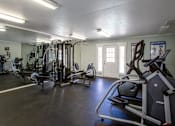 Thumbnail 27 of 34 - A spacious gym with a variety of equipment including treadmills, elliptical machines, and weight machines.