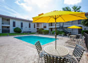 Thumbnail 2 of 34 - A yellow umbrella is over a table with chairs around a pool.