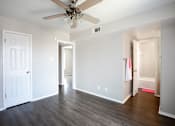 Thumbnail 18 of 34 - A room with a ceiling fan and wooden floors.